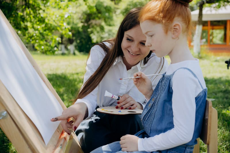 O voluntară îi arată unei fete cum să picteze